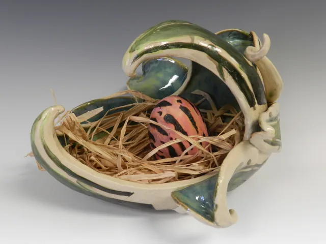 An open sculptural vessel filled with tangled threads and curved pieces.