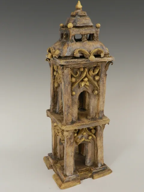 An intricate tower-like sculpture with stacked openings and pointed details.