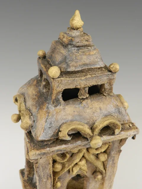 Close view of the textured upper section of a tower-like sculpture.