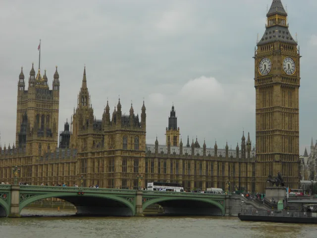 The Houses of Parliament beside the river beneath an overcast sky.