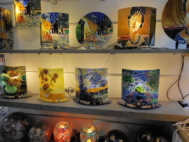 Decorated glass mugs displayed on illuminated shelves.