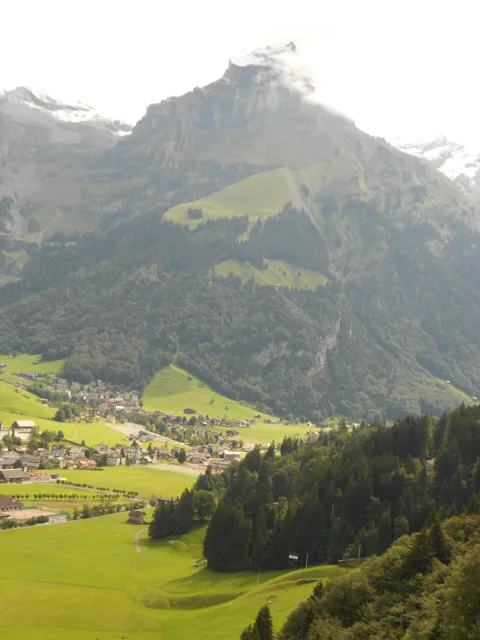 A steep mountain rising above a green valley.