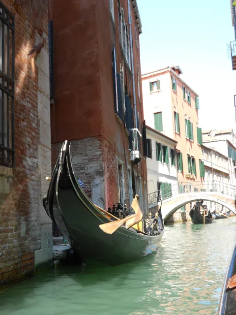 A narrow canal between buildings, viewed beneath a bridge.