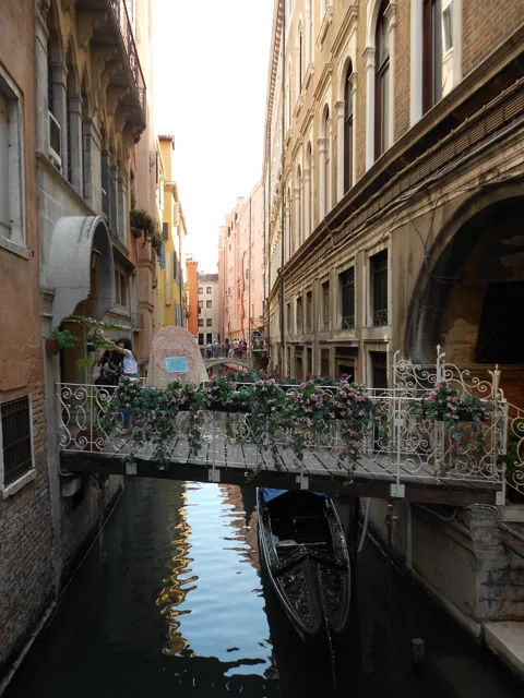 A narrow waterway and small bridge between tall buildings.