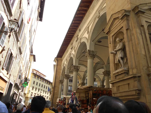 People walking through a narrow street lined with tall buildings.
