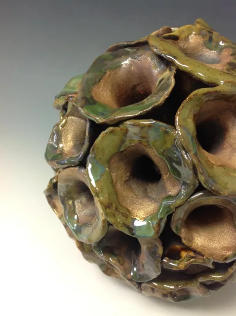 Close view of hollow rounded forms on a green and brown sculpture.