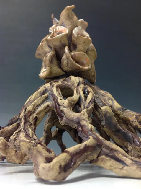 Close detail of a folded organic sculpture with green and brown surfaces.