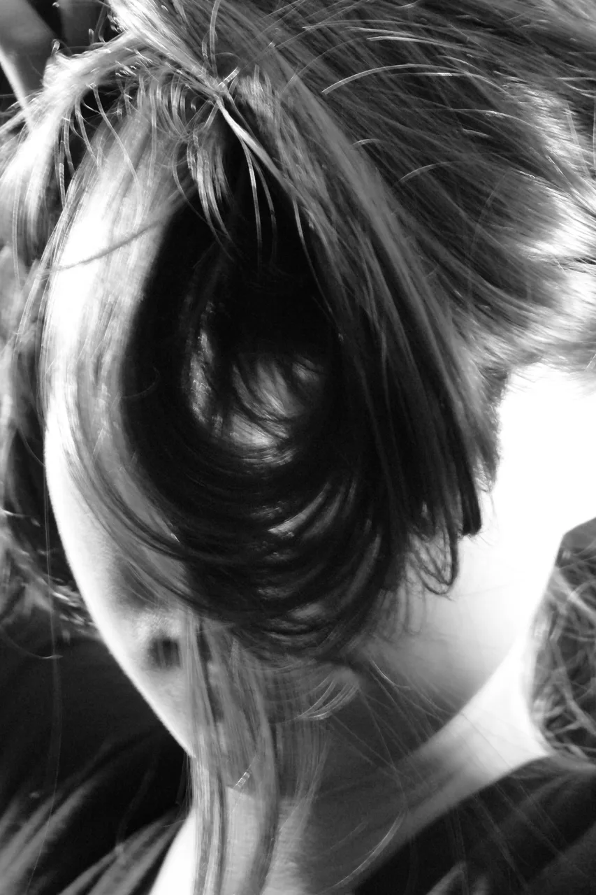 Black-and-white portrait with hair falling across the face.