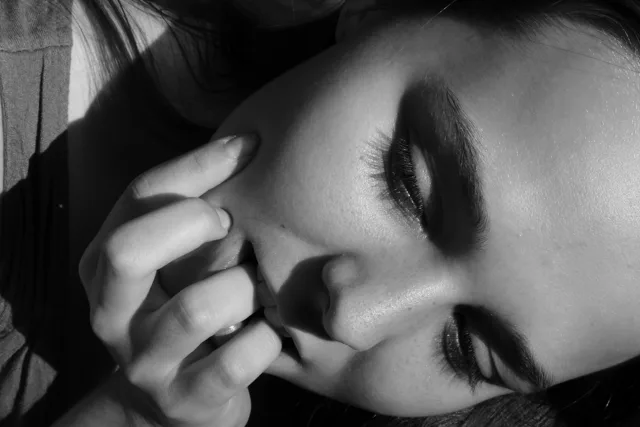 Black-and-white close-up of a face resting against a hand.