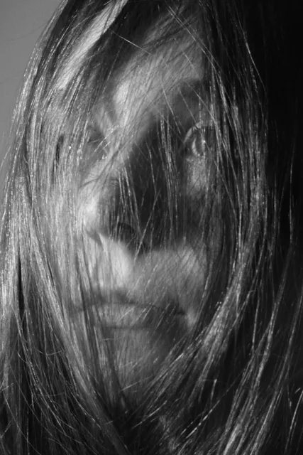 Black-and-white portrait with long hair covering part of the face.