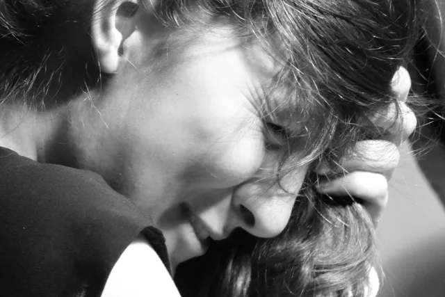 Black-and-white profile of a person with a hand against their face.