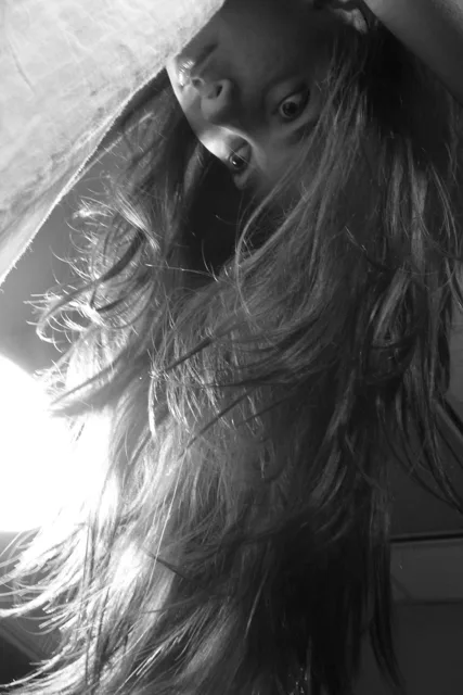 Black-and-white side portrait with strong light across the hair and shoulder.