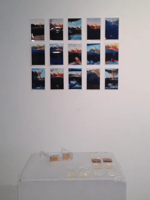 A grid of photographs displayed above small transparent objects on a white wall.