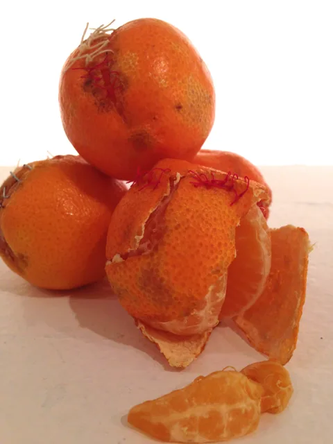 Stacked stitched oranges beside a loose curl of peel.