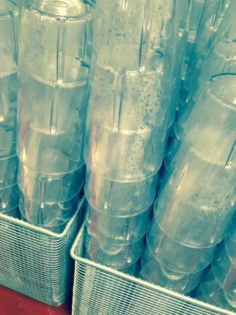 Stacks of clear drinking glasses seen through blue-green light.