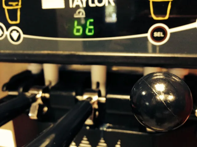 Close view of coffee-machine controls, a digital display, and a dark handle.