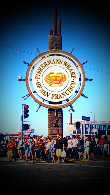 A colorful circular sign above a busy waterfront street.