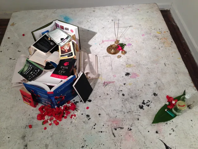 An overhead view of books and objects surrounded by red petals.