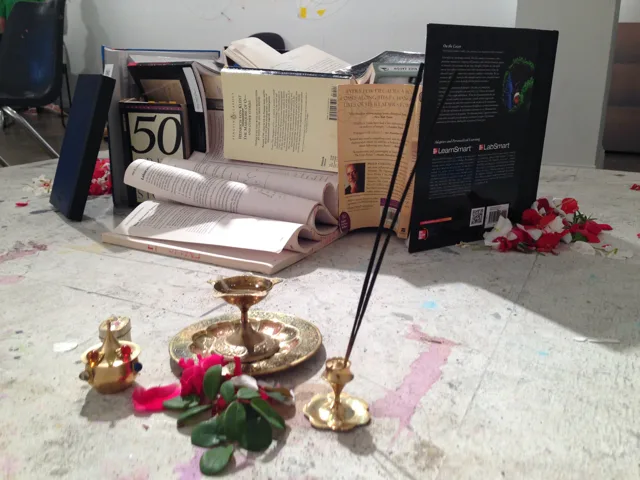 Brass vessels and scattered petals in front of a group of books.
